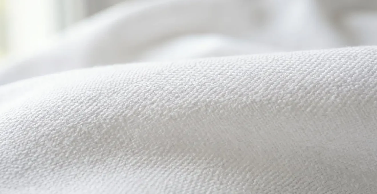 Gros plan sur le tissu de fond en percale de coton d'une couette 220x240, montrant le tissage serré et la texture douce
